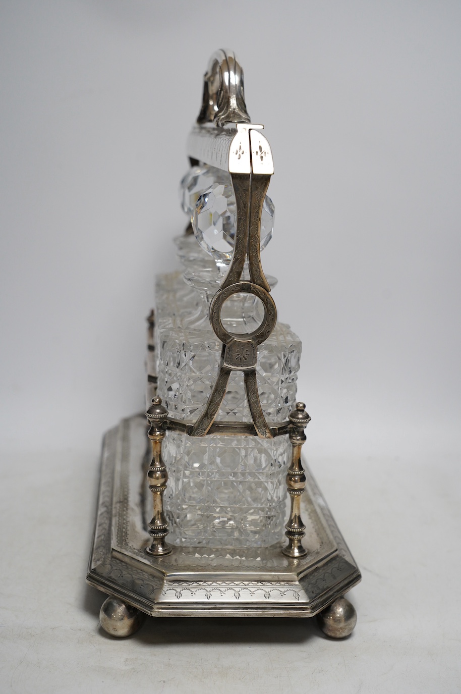 A silver plated three decanter tantalus with unusual duo swing handle locking mechanism, with key, 34cm tall. Condition - fair, a repair to one divider